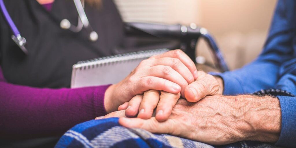 Caregiver and patient hold hands. 